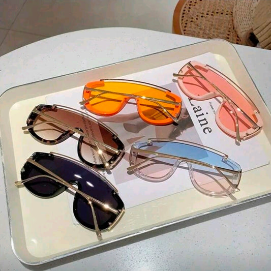Five pairs of sunglasses on a tray with a magazine underneath